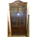 A 1930s stained oak cabinet bookcase with an arched top, over a pair of three-quarters height,