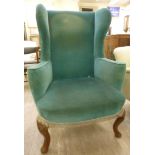 An early 20thC Georgian style wingback armchair, upholstered in turquoise dralon,