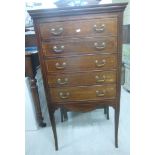 An Edwardian string inlaid and crossbanded mahogany music cabinet with a pierced, arched upstand,