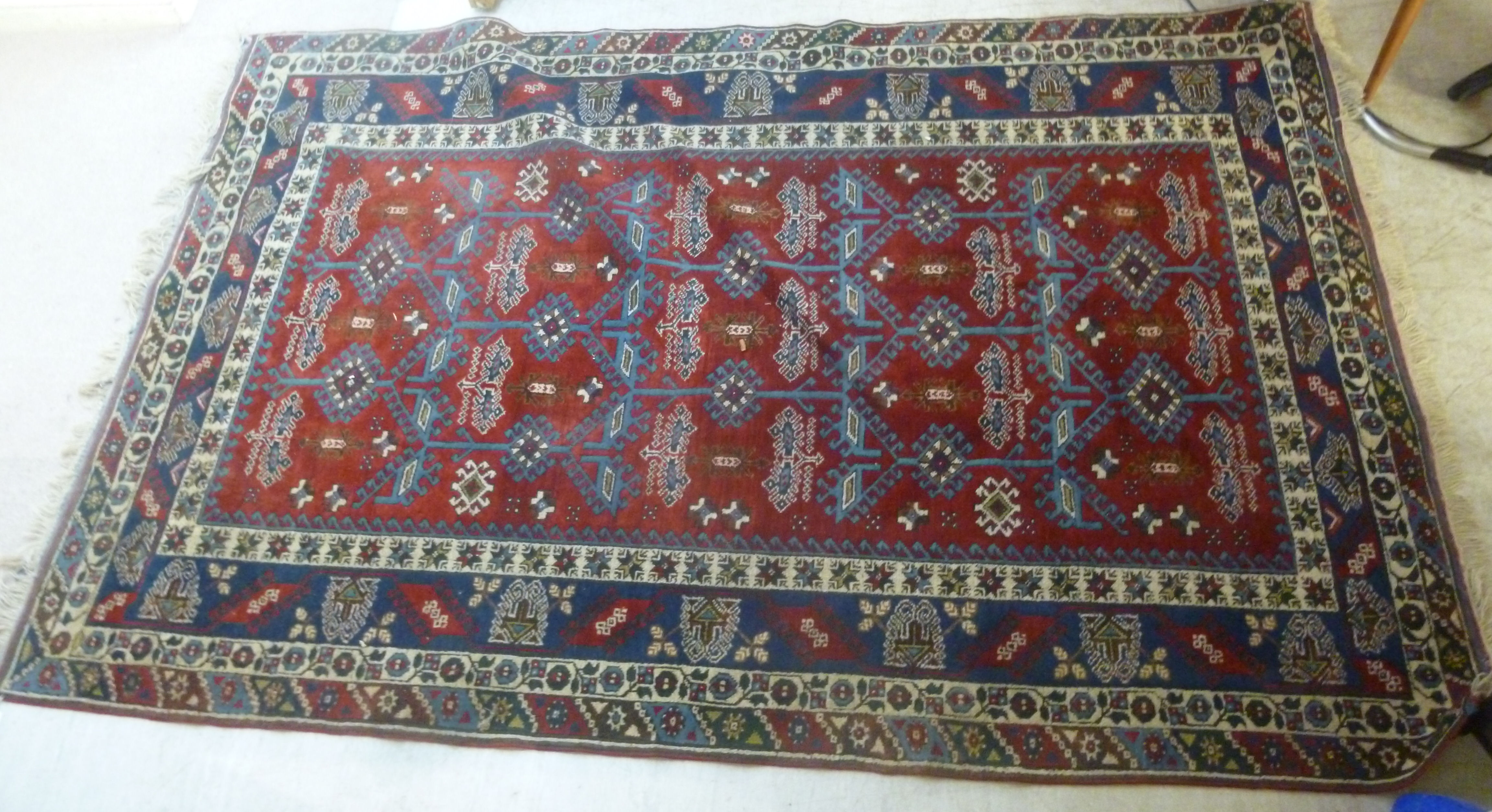 A Turkish carpet with stylised designs on a blue and red ground 110'' x 77''