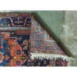 A Caucasian carpet with stylised designs on a blue and red ground 110'' x 61''