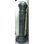 A two part turned granite pedestal with a stiff leaf carved ornament,