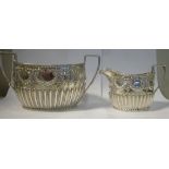 A late Victorian silver cream jug and matching twin handled sugar basin of oval, demi-reeded form,