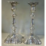 A pair of Georgian style silver candlesticks of lobed, square outline,