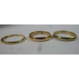 Two 14ct gold wedding rings and another in gold coloured metal