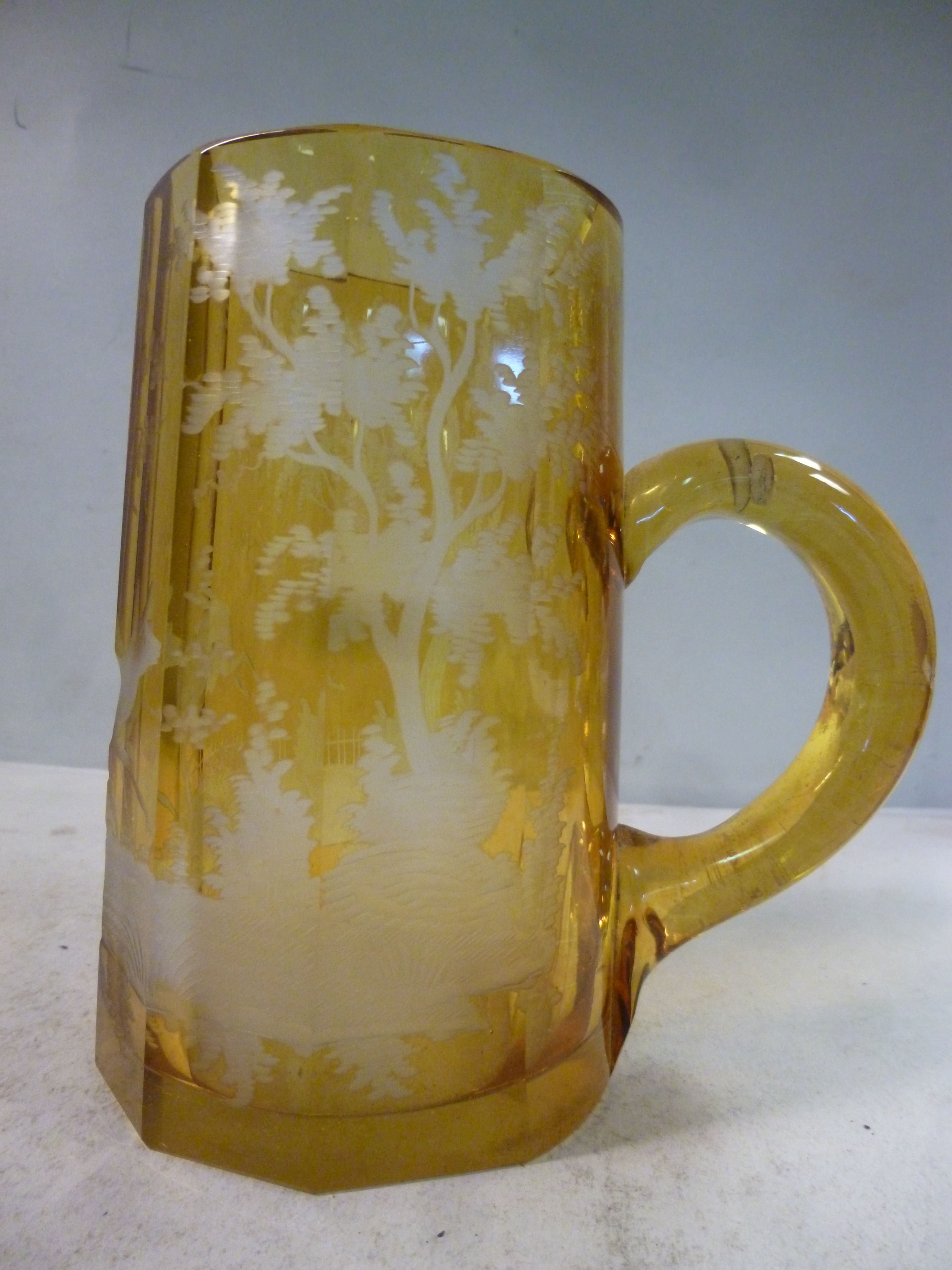 An early 20thC Bohemian amber coloured glass tankard of tapered, multi-panelled, facet cut form,