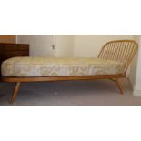 An Ercol pale coloured beech framed Windsor style daybed with an angled, round, spindled back end,