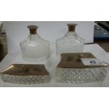 A pair of cut crystal perfume bottles with silver caps and two matching shallow boxes with silver