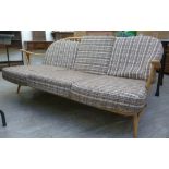 An Ercol pale coloured beech framed Windsor style settee with an angled, round,