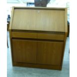 A modern teak bureau with a fall-flap, over two in-line drawers and a pair of cupboard doors,