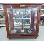 An early 20thC chemical balance, in a mahogany finished, glazed case,