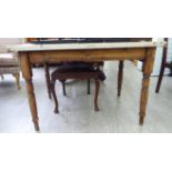 An early 20thC rustically constructed pine kitchen table, the planked top, over an end drawer,