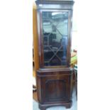 An early 20thC mahogany finished corner cabinet with a glazed door, over a panelled door,