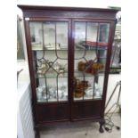 A 1920s mahogany display cabinet with a blindfret carved cornice, over two astragal glazed doors,
