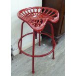 A modern cast iron red painted tractor design bar stool with a rotating height adjustable seat