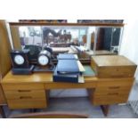 A 1970s Uniflex teak finished dressing table, surmounted by a triptych mirror, over seven drawers,