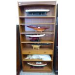 A modern teak bookcase with seven open shelves and a long drawer,