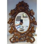 A late 19thC Black Forest bevelled oval mirror,