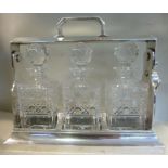 A mid 20thC silver plated tantalus with a lockable, folding bar and top handle,