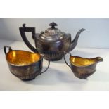An Edwardian bachelor's three piece silver tea set of oval, demi-reeded form comprising a teapot,