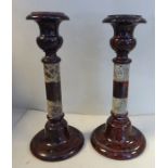 A pair of late 19thC mottled red and black marble candlesticks, each with a knopped stem,