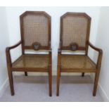 A pair of early 20thC Continental walnut framed and woven split cane panelled elbow chairs,
