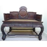 An early 20thC Chinese fruitwood window seat, having a panelled back and sides, raised with carved,