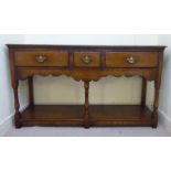 A modern Old English style oak dresser with three in-line drawers and cast brass bail handles on