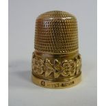 A 9ct gold thimble cast with a frieze of flora and foliage