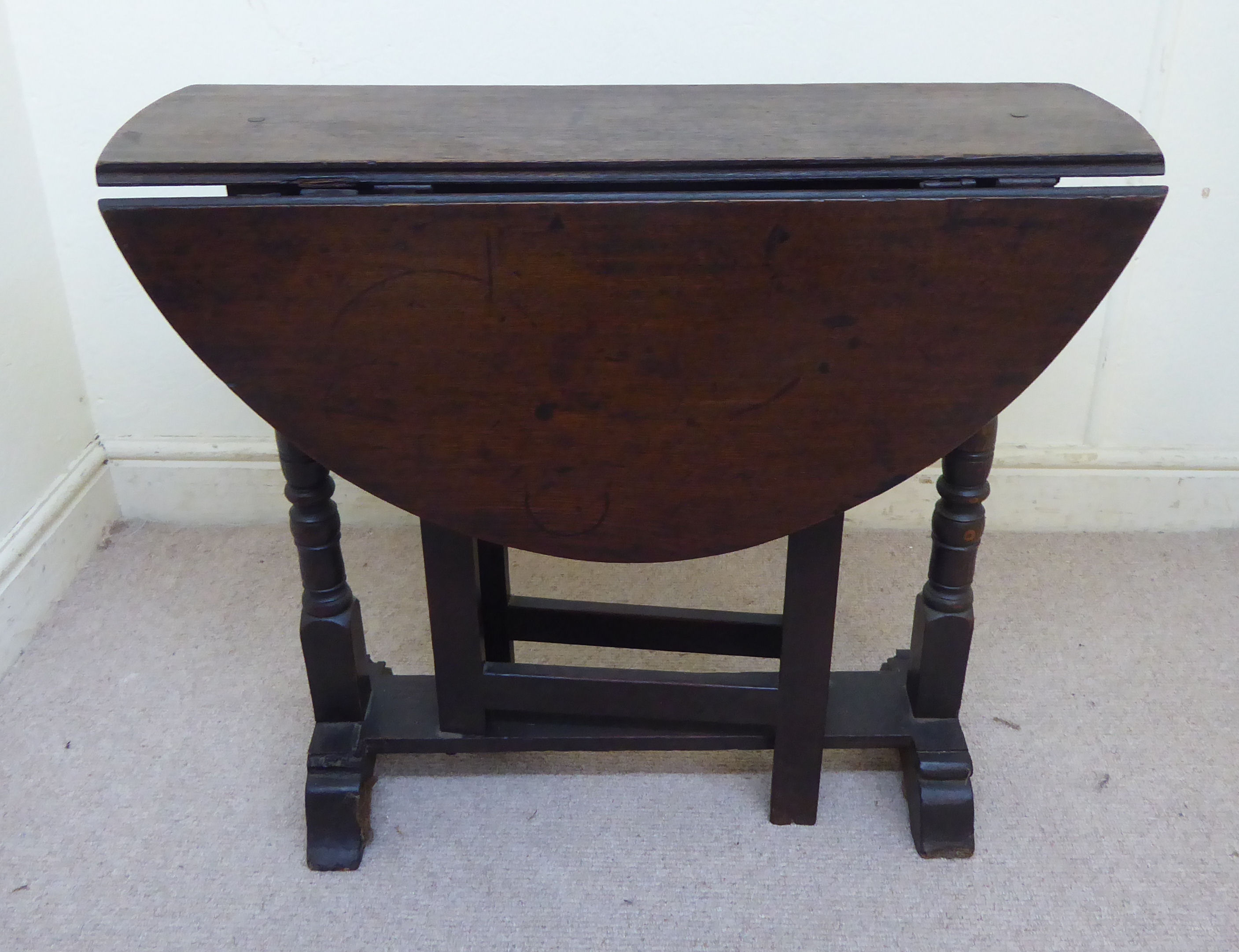 A late 18thC oak occasional table, the oval top with fall flaps,