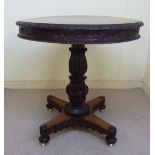 A William IV Colonial mahogany tip-top pedestal table with a stiff leaf and scroll carved border