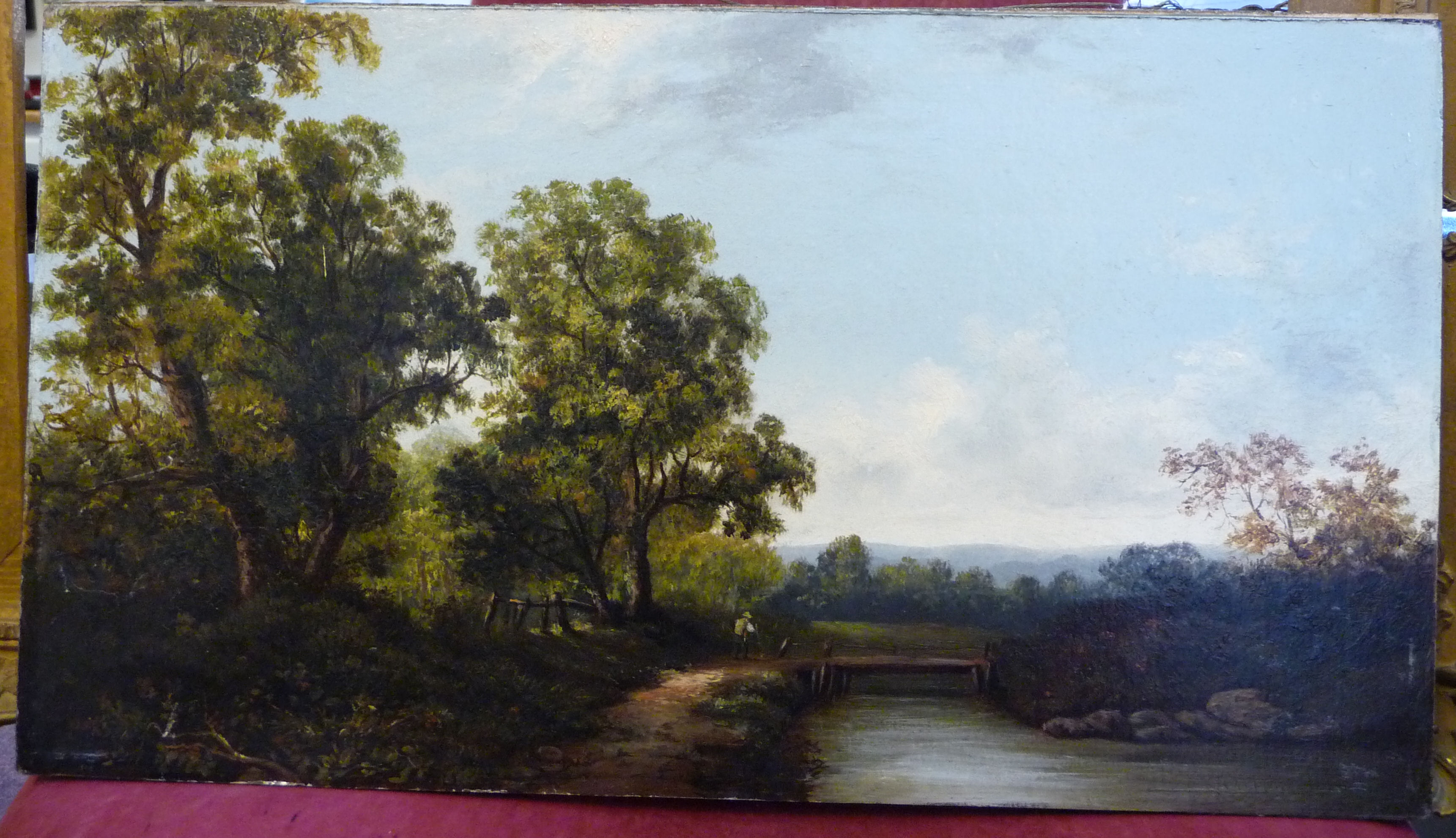 Early 20thC British School - a woodland landscape with a figure by a bridge over a river oil on