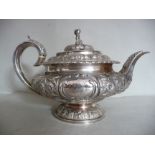 A George IV silver circular teapot of squat, bulbous form with a swept spout and C-scrolled handle,