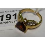 A 9ct gold ring set with a heart shaped garnet and diamond chip shoulders