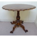 A mid Victorian walnut centre table, the oval top with a moulded wavy edge, over a baluster column,