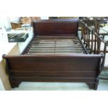 A modern mahogany finished sleigh bed with twin C-scroll ends, raised on bracket feet,