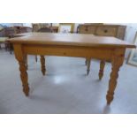 A modern waxed pine farmhouse style kitchen table, the top with rounded corners,