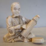 An early 20thC Japanese carved and stained ivory figure, a craftsman, seated crosslegged,