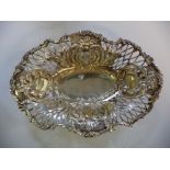 An Edwardian silver basket of oval form with decoratively scroll embossed and pierced sides,