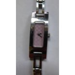 A Gucci lady's stainless steel cased pink wristwatch, faced by a black dial,