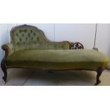 A late Victorian fruiting vine carved walnut framed chaise longue with a button upholstered green