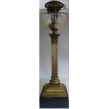 An early 20thC style lacquered brass oil lamp, the fitting set in a facet cut clear glass reservoir,