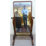 An early Victorian mahogany framed cheval mirror, the rectangular plate pivoting on scrolled horns,