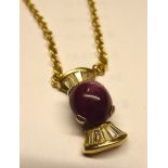 An 18ct gold pendant, set with a cabochon cut ruby, flanked by twelve baguette cut diamonds,