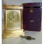 An early 20thC gilt metal cased carriage clock with a folding top handle,