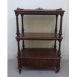 A late Victorian figured walnut three tier whatnot with a fretworked gallery and turned uprights,