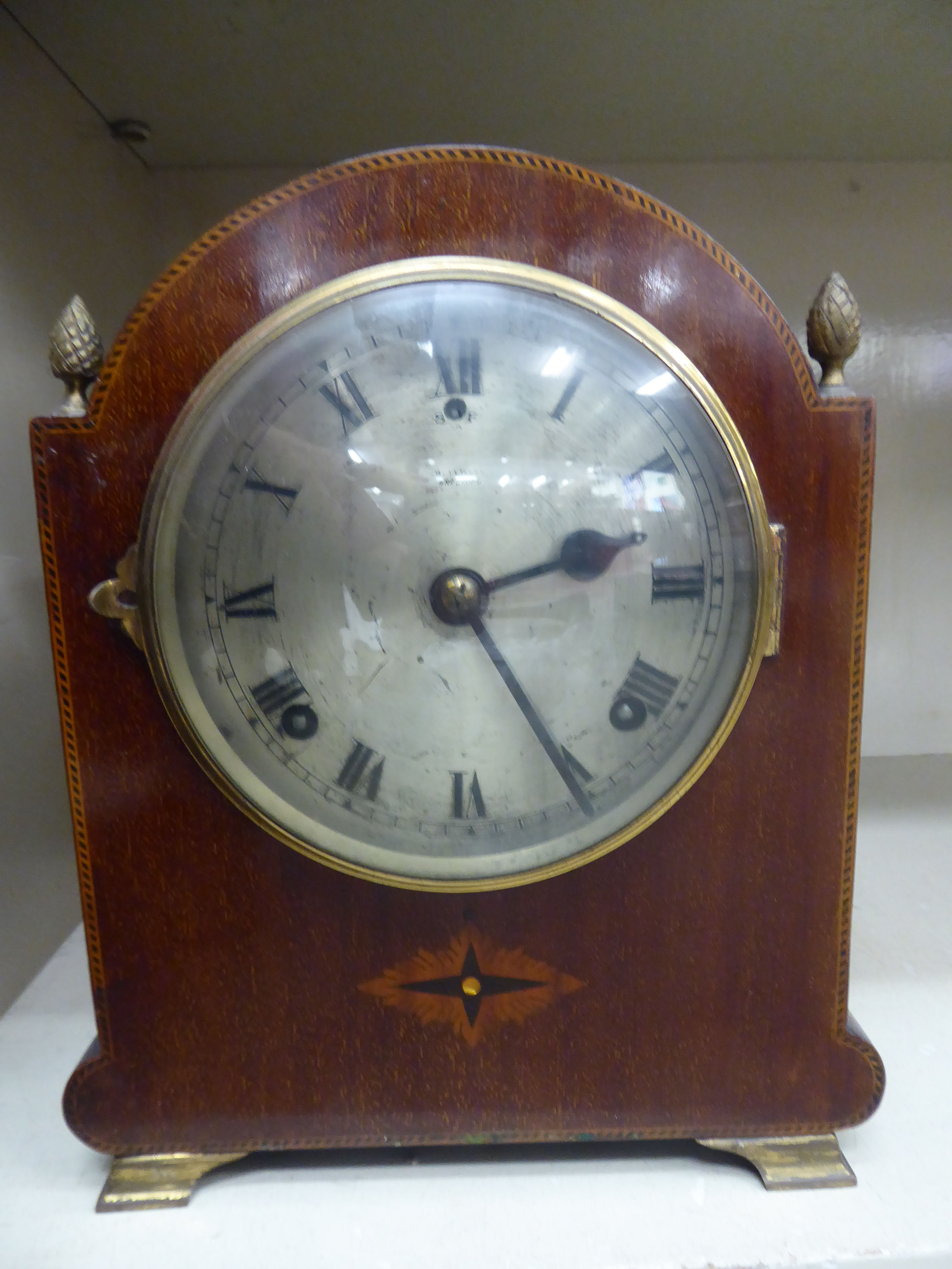 An Edwardian mahogany mantel clock with lacquered brass mounts and string inlaid ornament,