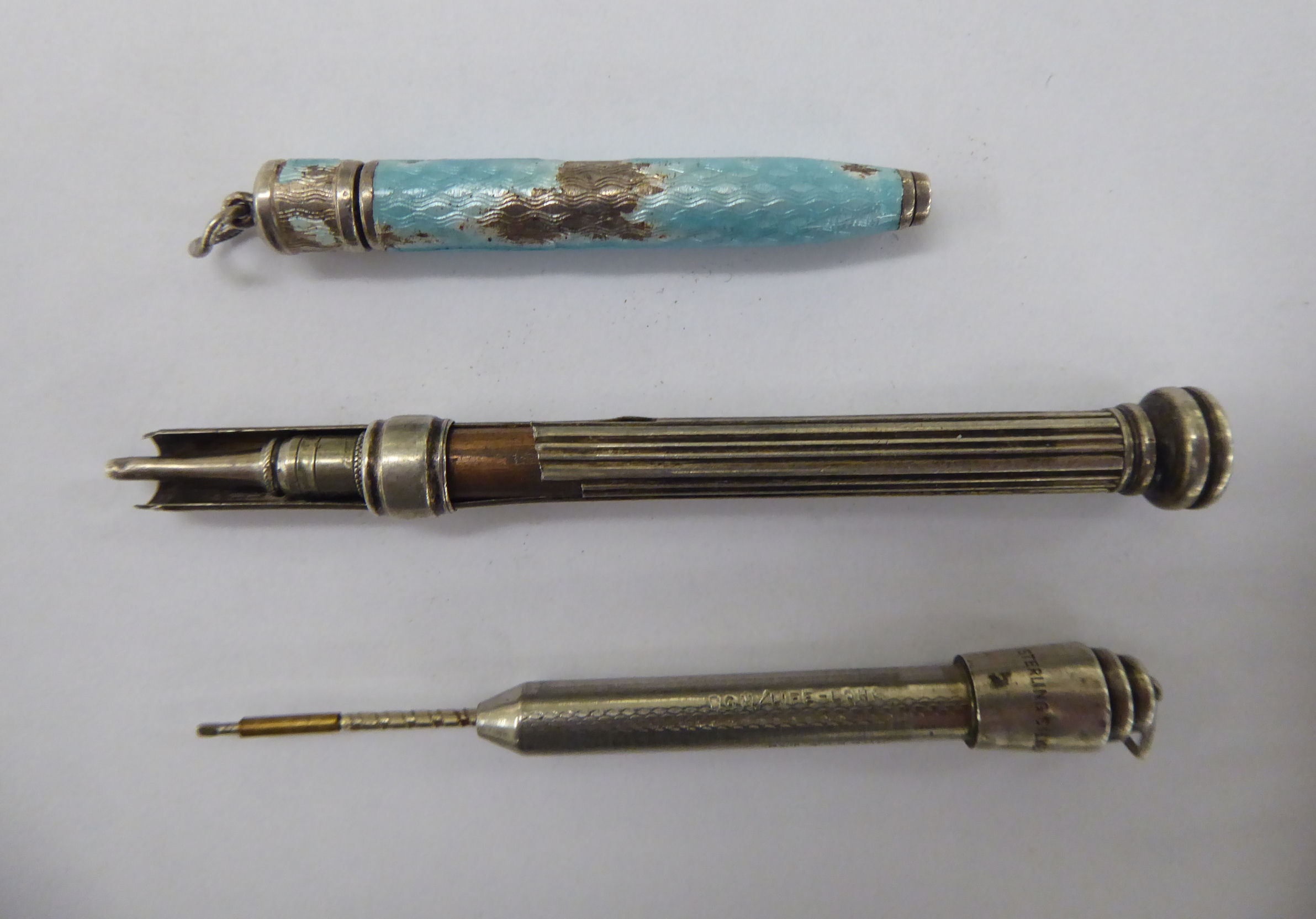 Three white metal cased pencils,