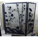 A modern black painted metal triptych firescreen with applied flora,