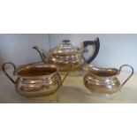 A three piece silver tea set of elongated oval ogee form comprising a teapot with a swept spout,